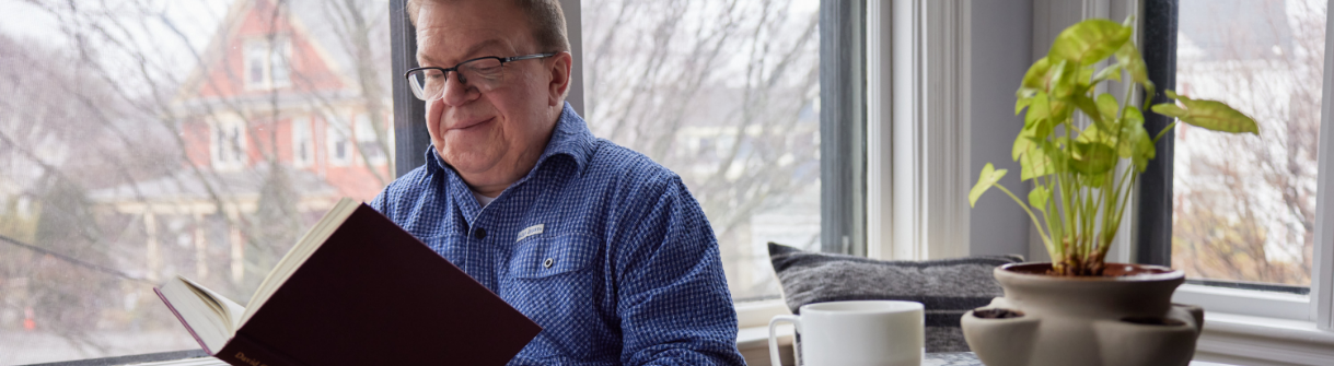 Jason, adult living with hunter syndrome, reading a book