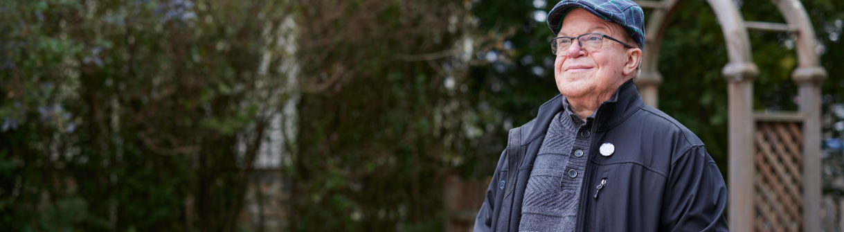 Jason, an adult with Hunter syndrome, smiling proudly and looking into the distance