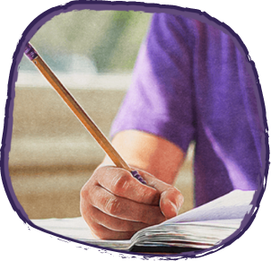 Boy in purple shirt writing in school book